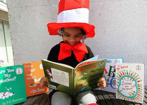 child with red hat reading a book
